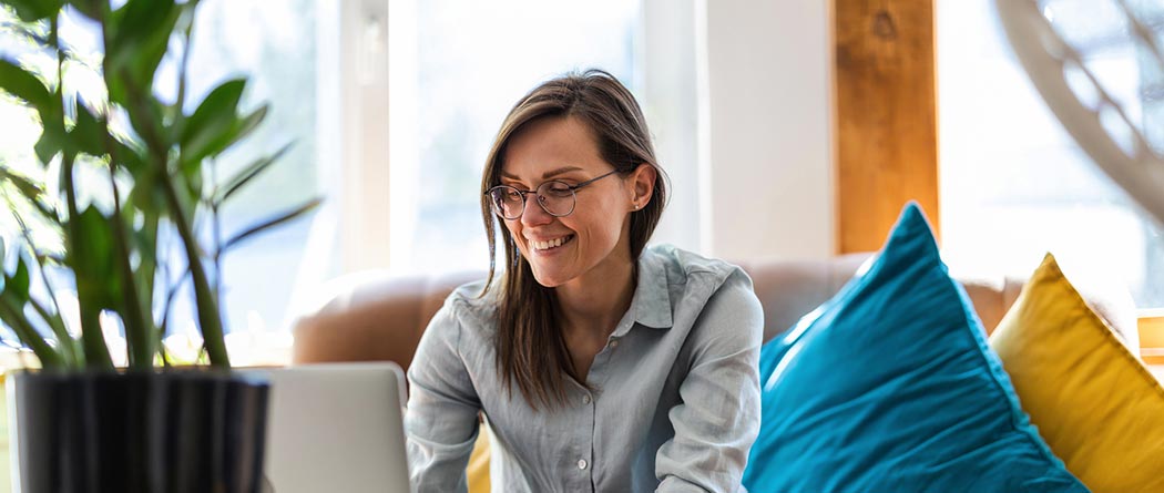Woman sitting on couch using laptop.